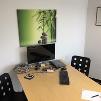 Holzschreibtisch, Computerbildschirm und ein Bild an der Wand